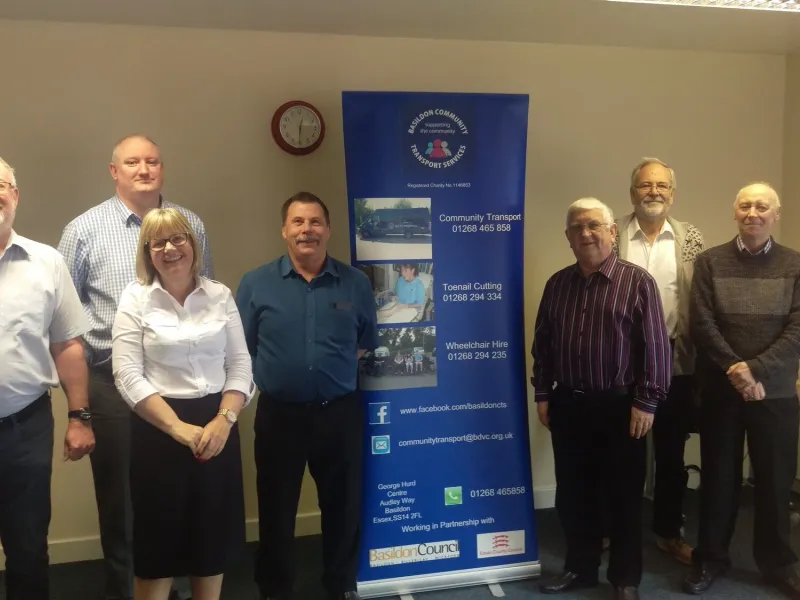 Seven members of the BCTS team standing in the office beside the charity's banner