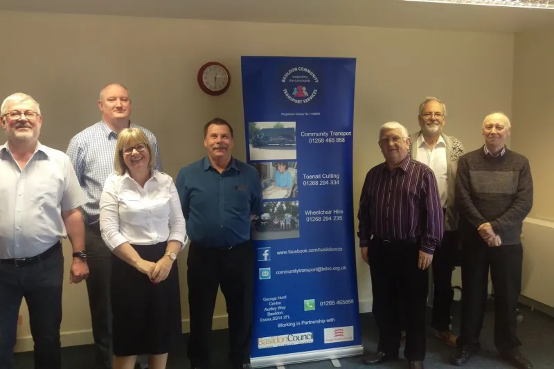 Seven members of the BCTS team standing in the office beside the charity's banner
